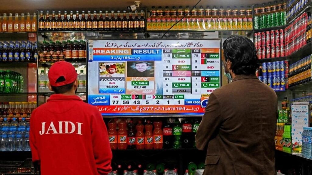 People watch latest election results live on a television at a shop, a day after Pakistan's national elections in Lahore on February 9, 2024. (AFP)