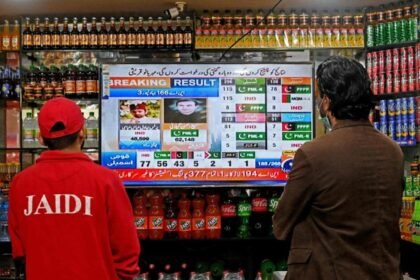 People watch latest election results live on a television at a shop, a day after Pakistan's national elections in Lahore on February 9, 2024. (AFP)